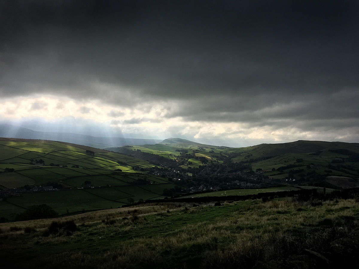 Lantern Pike to Hayfield - Photo of Hayfield in the Peak District from the side of Lantern Pike with a moody sky and rays of sunlight - photo by gavstretchy